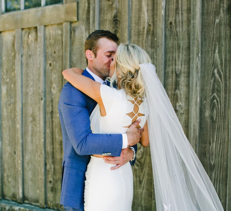 Bride in Noel and Jean Bridal Separates and Wedding Veil Embracing Groom in Blue Suit Supply Wedding Suit