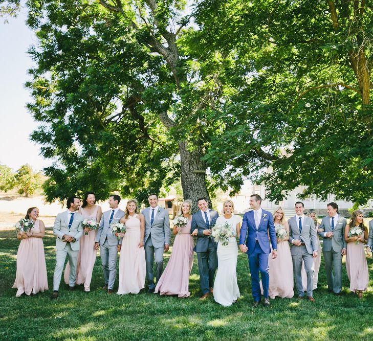 Wedding Party Portrait with Bridesmaids in Pink, Groomsmen in Grey and Groom in Blue Suit