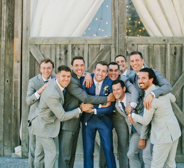 Groom in Blue Suit Surrounded by Groomsmen in Grey Suits