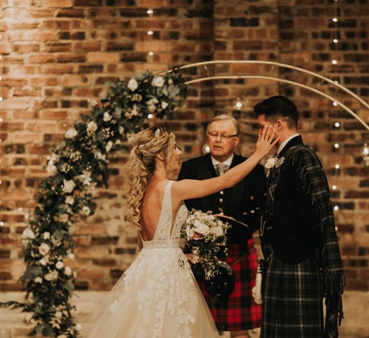 Bride and groom get emotional during ceremony with gold flower arch