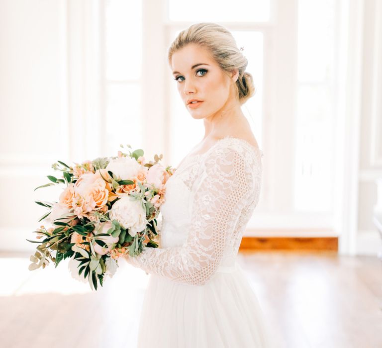 Bride in Lace Long Sleeve Wedding Dress Holding Peach and White Bouquet