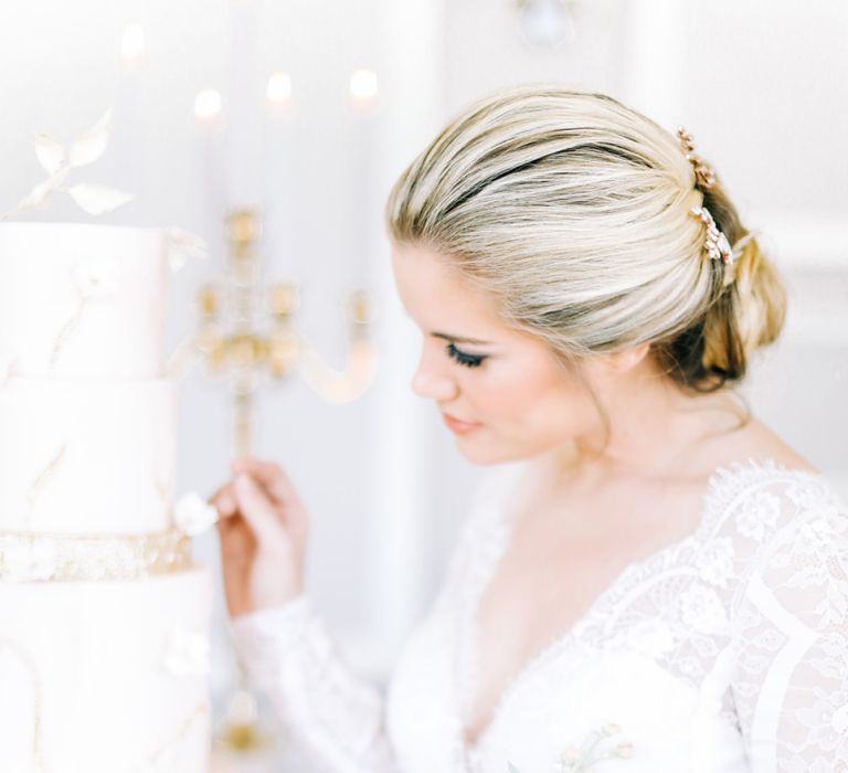 Bride in Lace Long Sleeve Wedding Dress Looking at Elegant Wedding Cake