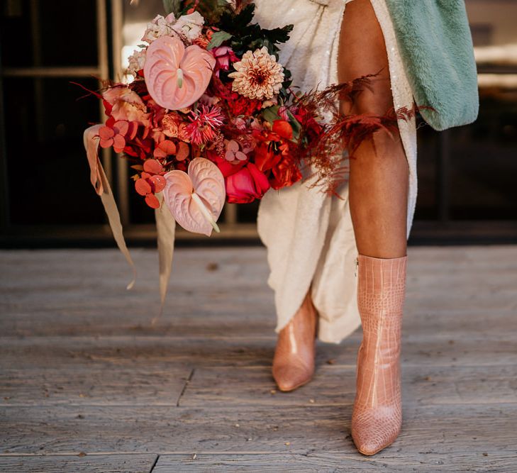 Stylish Bride in Pink Croc Bridal Boots and Blue Teddy Coat Holding a Red and Pink Bridal Bouquet with Anthurium Stems