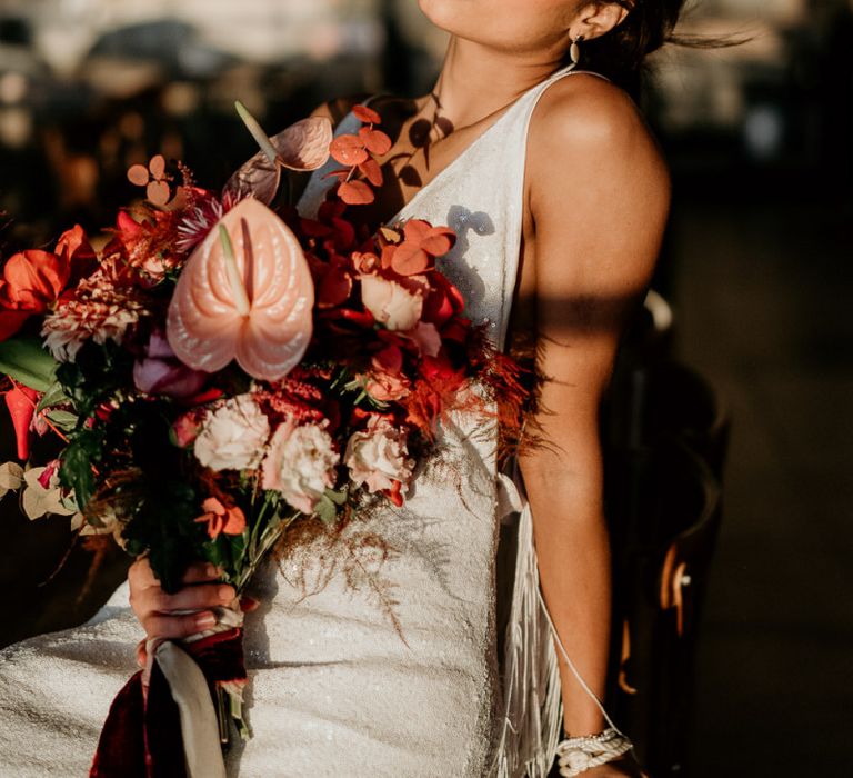 Modern Bride in Minimalist Wedding Dress Holding a Red and Pink Bridal Bouquet with Anthurium Flower Stems