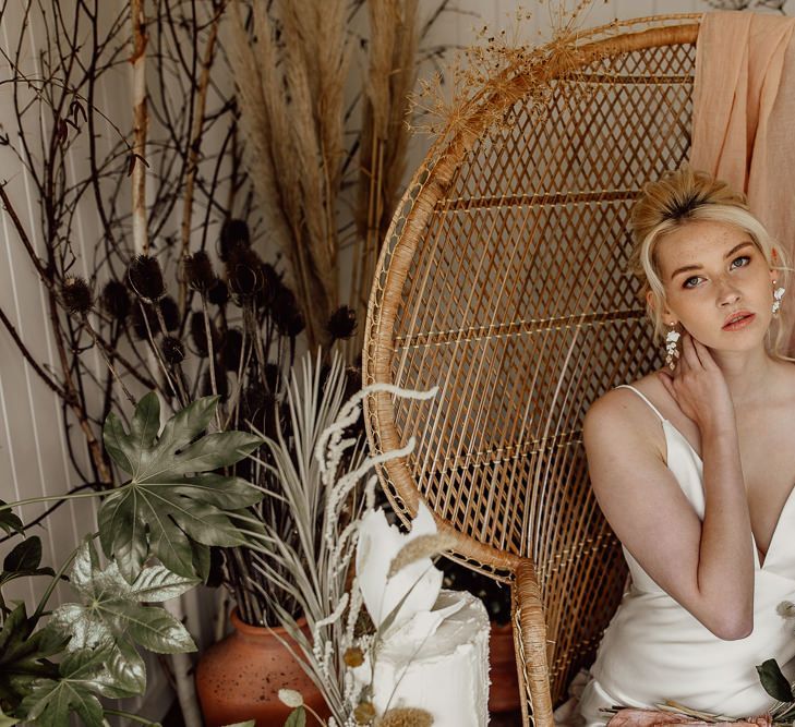 Bride with Up Do and Chandelier Earrings Sitting on a Peacock Chair