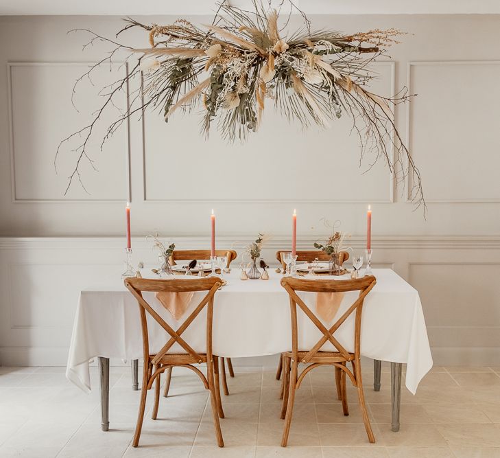 Minimalist Tablescape with Hanging Flower Installation, Wooden Chairs &amp; Peach Taper Candles