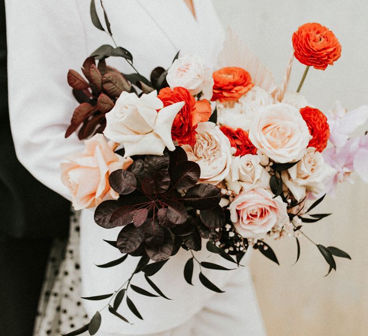 Winter wedding bouquet with red ranunculus and pink roses