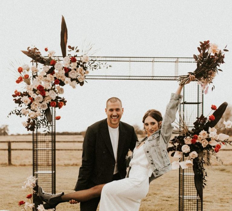 Bride in minimalist wedding dress, boots and denim jacket at Godwick Great Barn