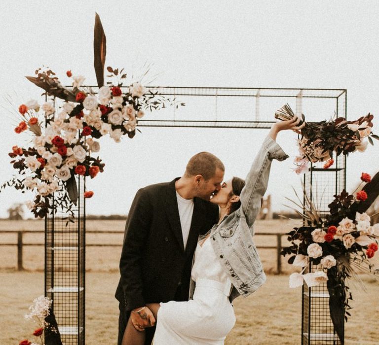 Stylish bride and groom kissing at the altar at Godwick Great Barn