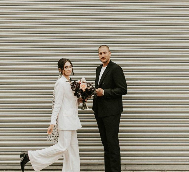 Stylish bride in trouser suit with groom in white t-shirt and blazer