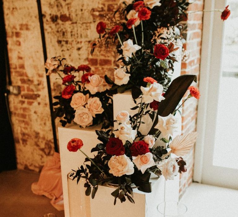 floral arrangements on plinths decorated with candles at Godwick Great Barn