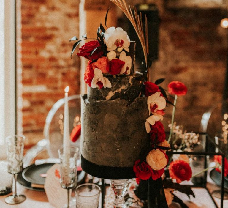 Black wedding cake with pink and red wedding flower decor