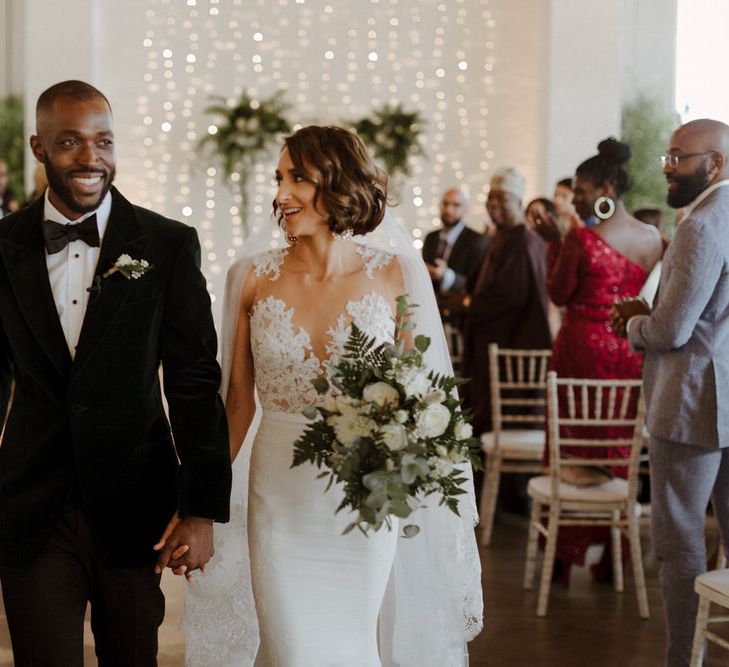 The Ceremony. Bride wears dress by Pronovias. Groom wears green velvet blazer from Gieves &amp; Hawkes in this Green And White Luxe, City Wedding. Photography by The Curries.