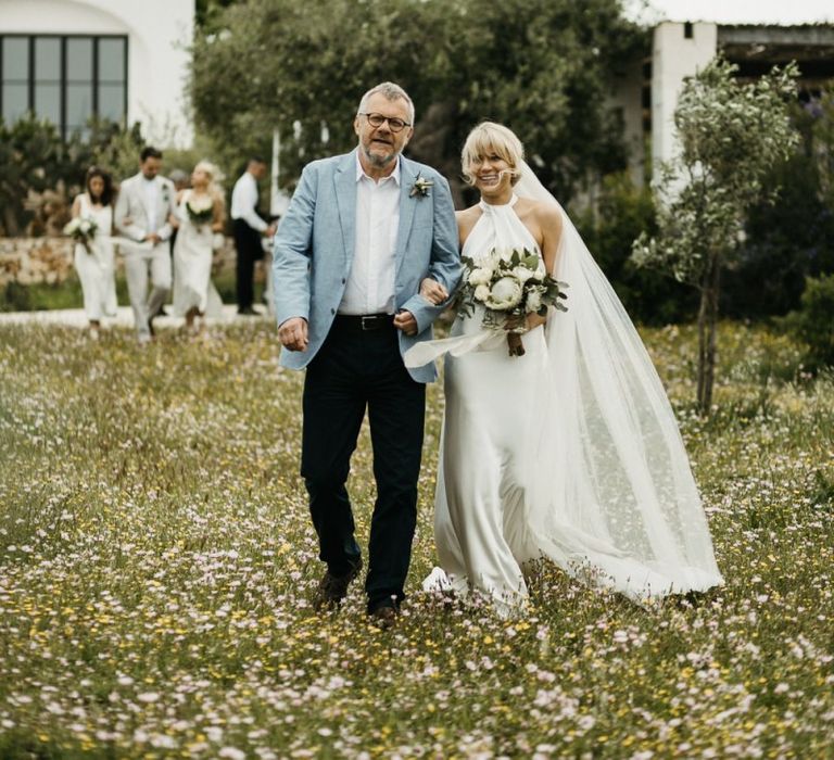 Bride walks down aisle at outdoor ceremony