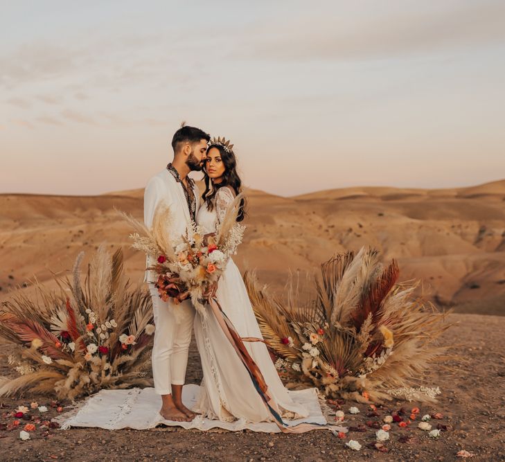 Boho bride and groom standing at the pampas grass and rug altar