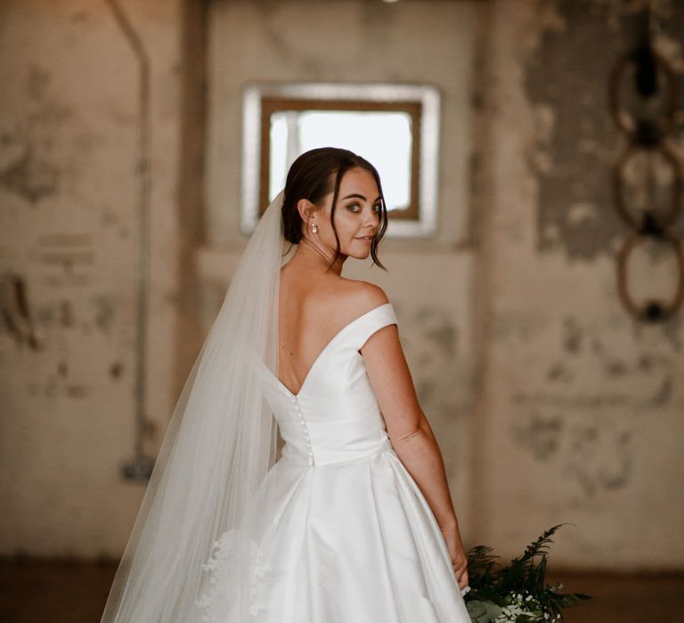 Off-the-shoulder wedding dress with bridal updo and veil