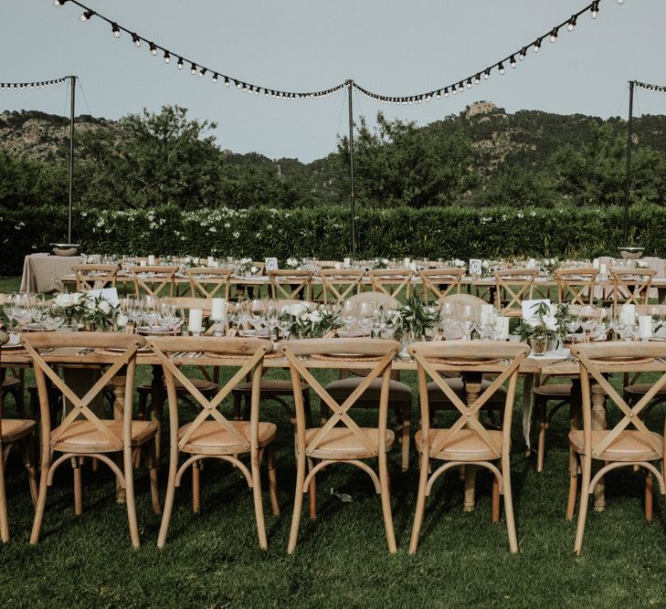 Outdoor Destination Wedding Reception with Wooden Table and Chairs and Festoon Lights