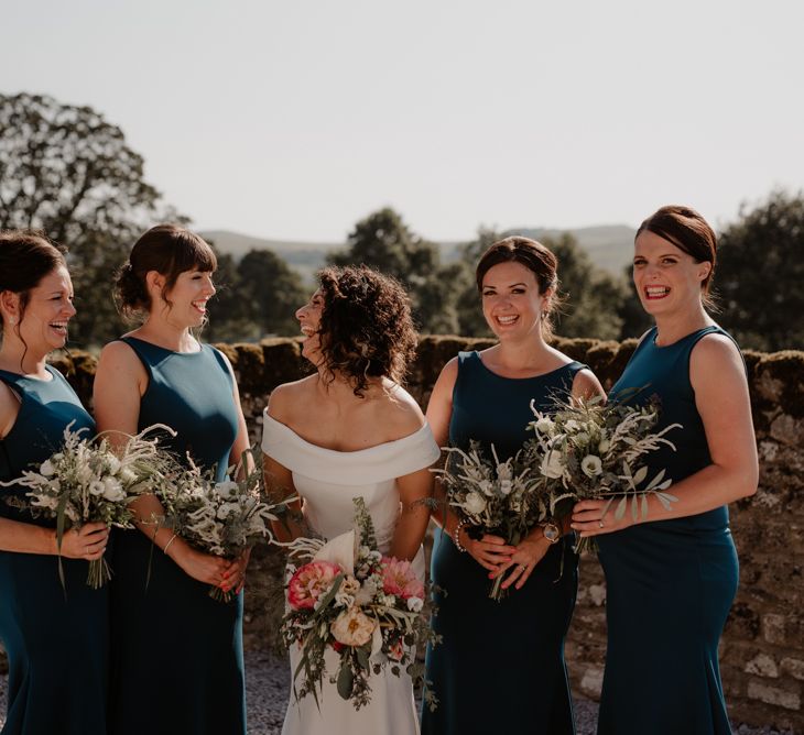 Bridesmaids in teal dresses and bride in Suzanne Neville wedding dress