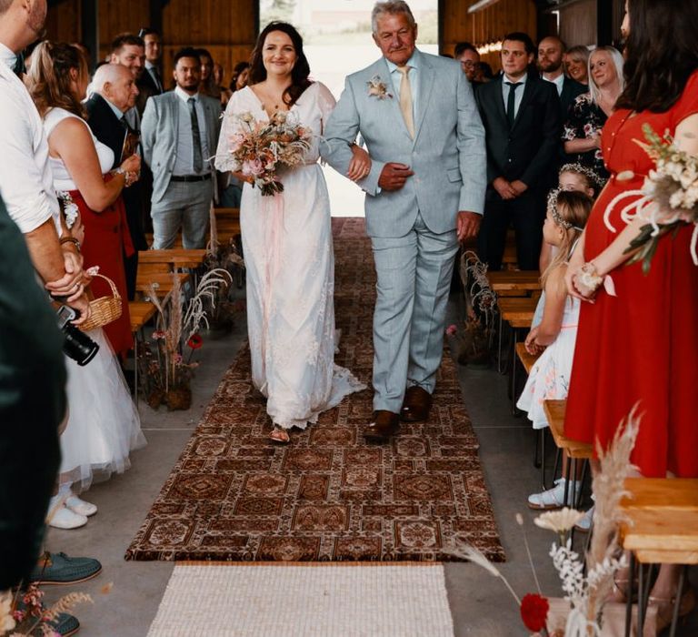 Bride walks down the aisle at The Giraffe Shed decorated in Autumn wedding colours