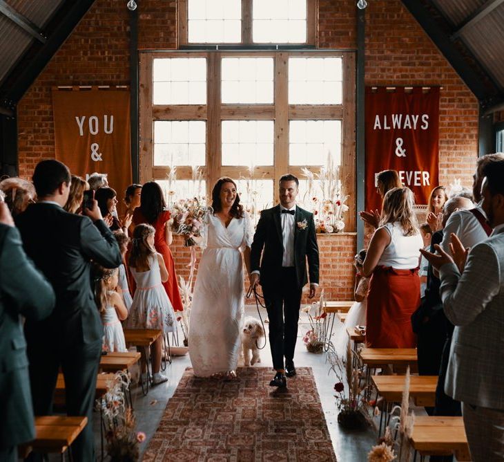 Bride and groom walk down the aisle with pet dog