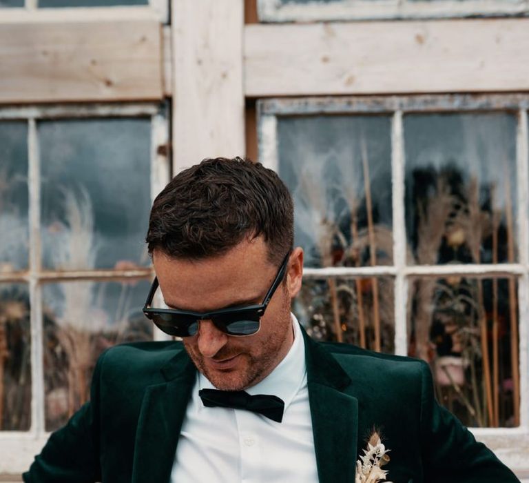 Groom in tuxedo and sunglasses with dried flower buttonhole