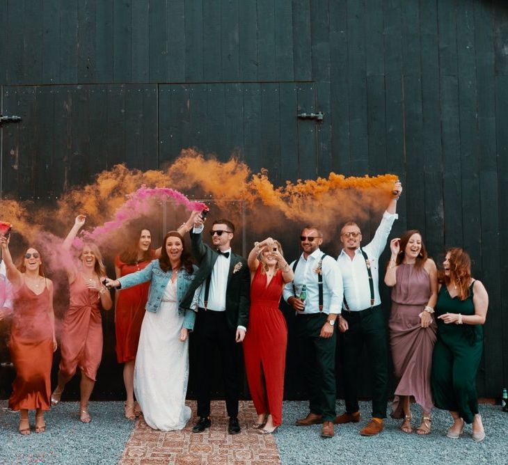 Guests wave smoke flares in Autumn wedding colours