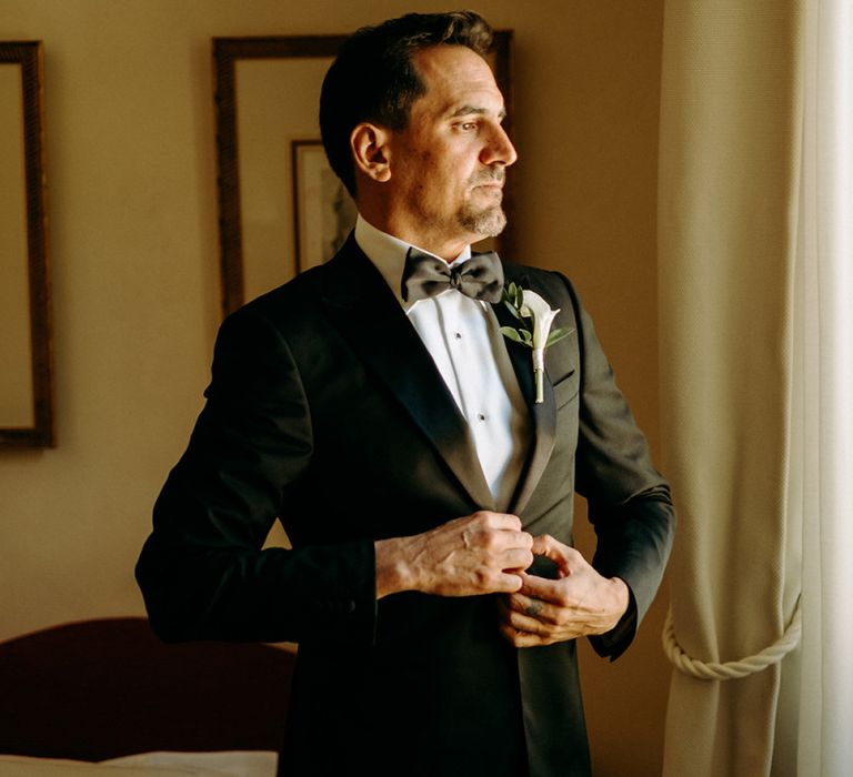 Groom preparations in black tie wedding suit