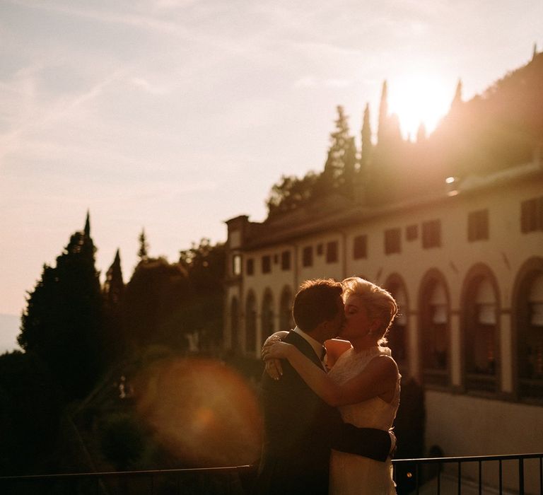 Bride and groom kiss in front of sunset in Italy