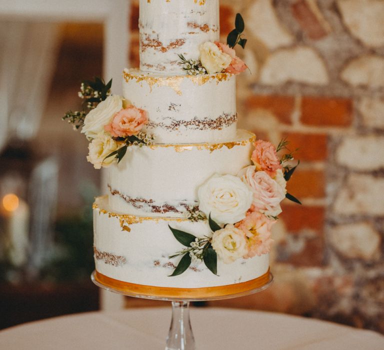 Beautiful semi-naked wedding cake with copper detail and floral decor