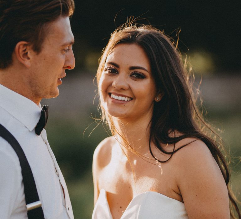 Bride in strapless fishtail wedding dress with groom in tuxedo