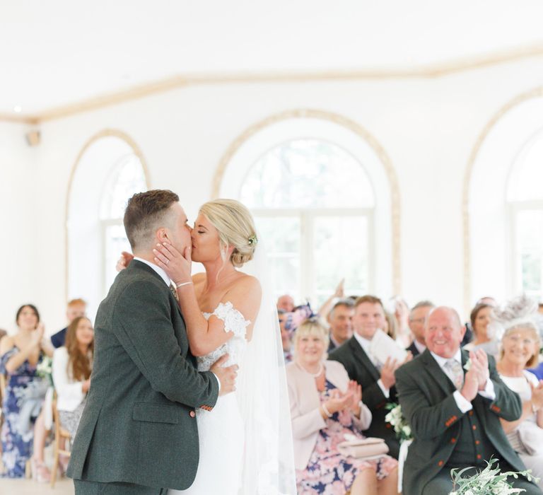 Wedding Ceremony with Bride in Lace St Patrick Wedding Dress and Groom in Grey Empire Outlet Suit Kissing