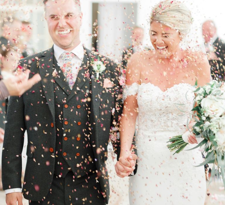 Confetti Exit with Bride in Lace St Patrick Wedding Dress and Groom in Grey Empire Outlet Suit