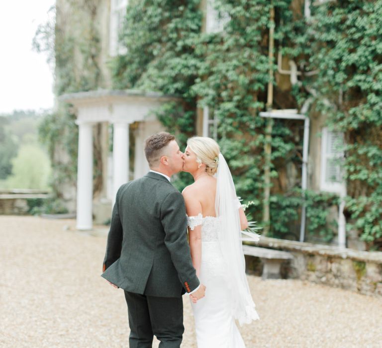 Bride in Off the Shoulder St Patrick Wedding Dress and Groom in Grey Suit  Kissing