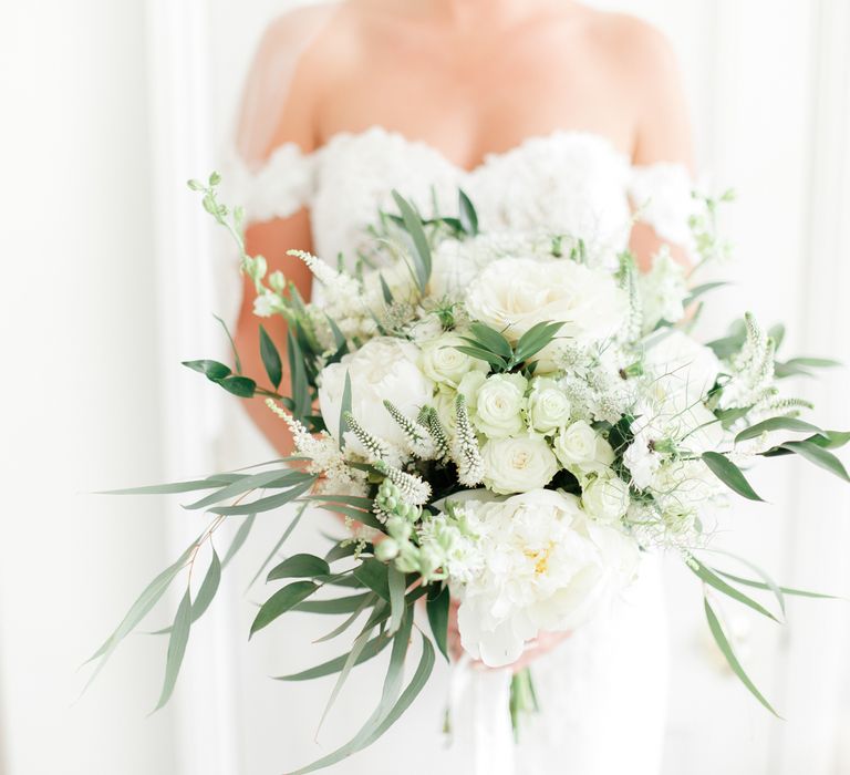 Bride in Off the Shoulder Wedding Dress Holding a White and Green Wedding Bouquet