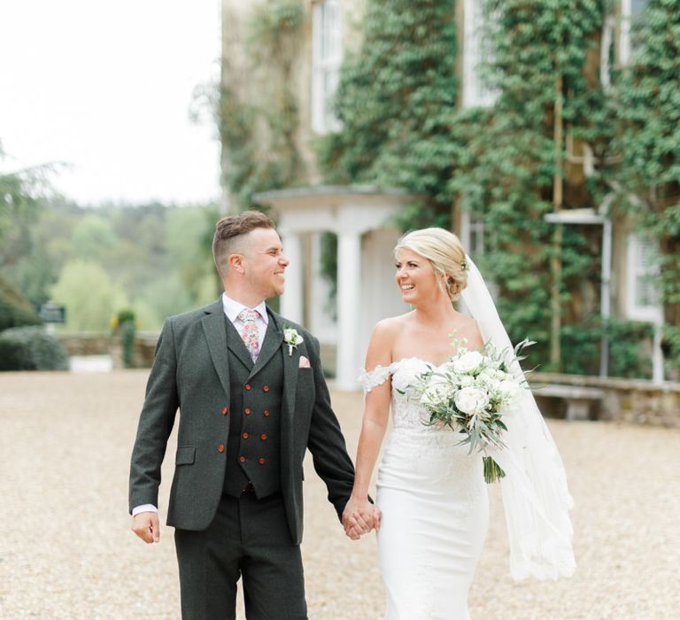 Bride in St Partrick Wedding Dress and Groom in Three-piece Wedding Suit Holding Hands