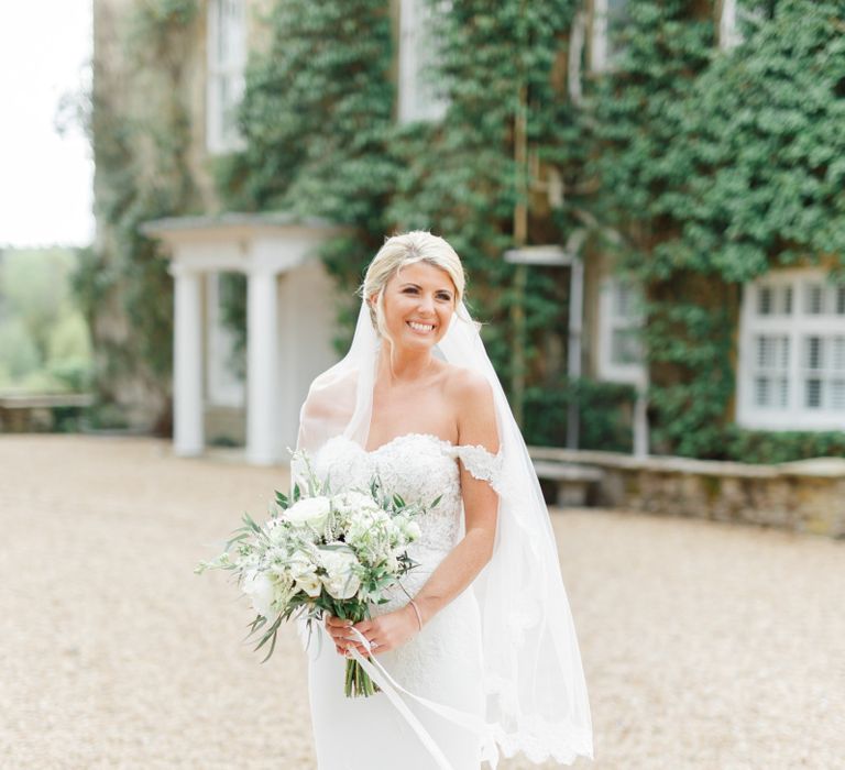 Beautiful Classic Bride in a Off the Shoulder St Patrick Wedding Dress Holding a Green and White Wedding Bouquet