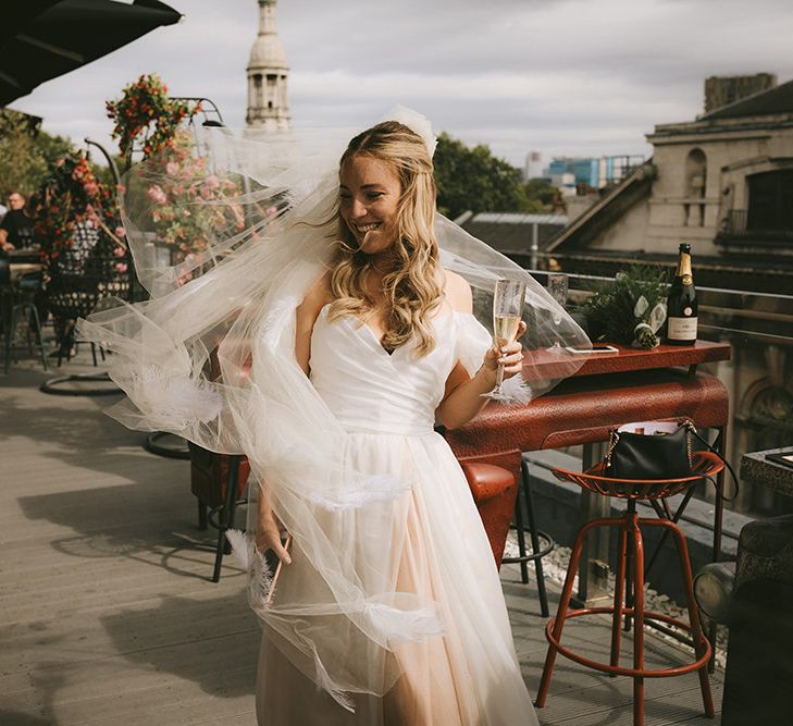 Pre-Ceremony Champagne | Bride in Bespoke Wedding Gown with Blush Underskirt and One Off Shoulder Strap | Fingertip Length Veil Customised with Feathers | Half Up Half Down Bridal Hair | Bike Shed Motorcycle Club Wedding for ELLE Digital Editor | Nigel John Photography