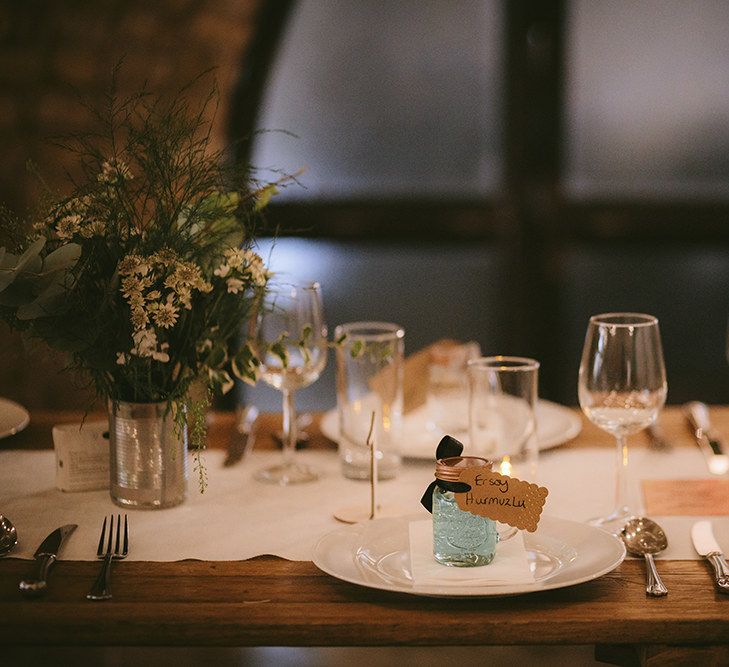 Wedding Reception Décor | Place Setting | Wooden Trestle Tables with White Runner | White Flowers, Ferns and Foliage in Tin Can | Bike Shed Motorcycle Club Wedding for ELLE Digital Editor | Nigel John Photography