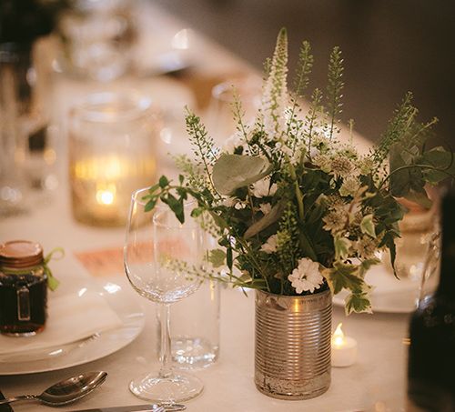 Wedding Reception Décor | Wooden Trestle Tables with White Runner | White Flowers, Ferns and Foliage in Tin Can | Tea Lights | Bike Shed Motorcycle Club Wedding for ELLE Digital Editor | Nigel John Photography