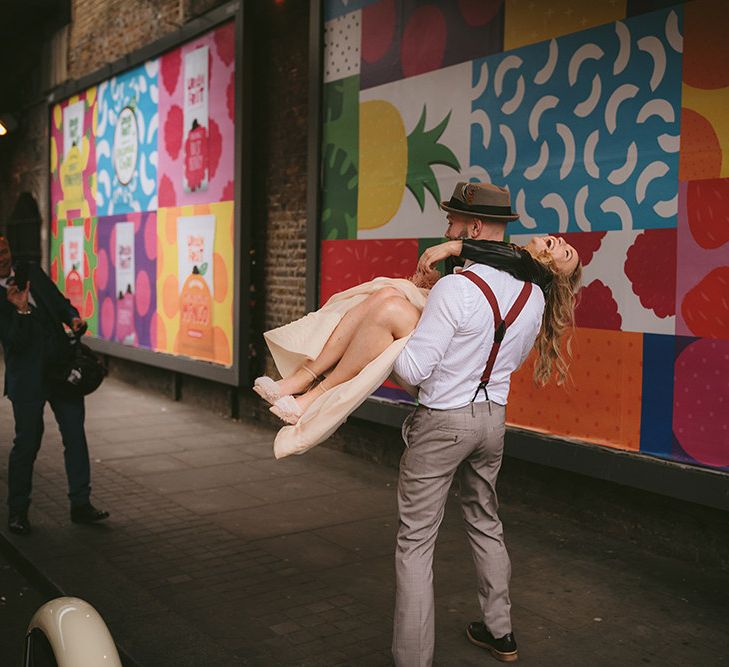 Groom in Grey Puppy Tooth Check Two-Piece Paul Smith Suit with Amber Tie Pin, Pocket Square, Braces and Hat with Feather | Bride in Bespoke Wedding Gown with Blush Underskirt and One Off Shoulder Strap | Thug Wife Leather Bridal Jacket | Bike Shed Motorcycle Club Wedding for ELLE Digital Editor | Nigel John Photography