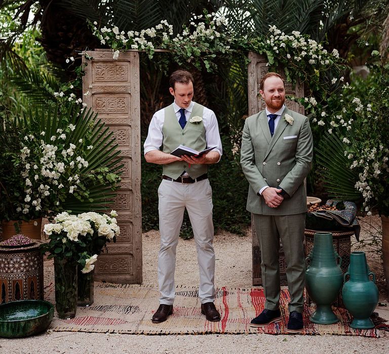 Outdoor Wedding Ceremony | Wooden Door Altar Decor | Groom in Green Beggars Run Suit |  Paradise Destination Wedding at Jnane Tamsna in Marrakech, Morocco | Nordica Photography | Matteo Castelluccia Film