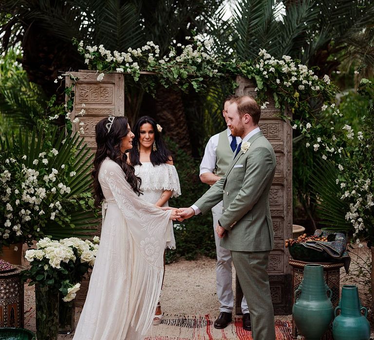 Outdoor Wedding Ceremony | Moroccan Rugs, Wooden Door Altar Wedding Decor | Bride in Rue de Seine Bridal Gown | Groom in Green Beggars Run Suit | Paradise Destination Wedding at Jnane Tamsna in Marrakech, Morocco | Nordica Photography | Matteo Castelluccia Film