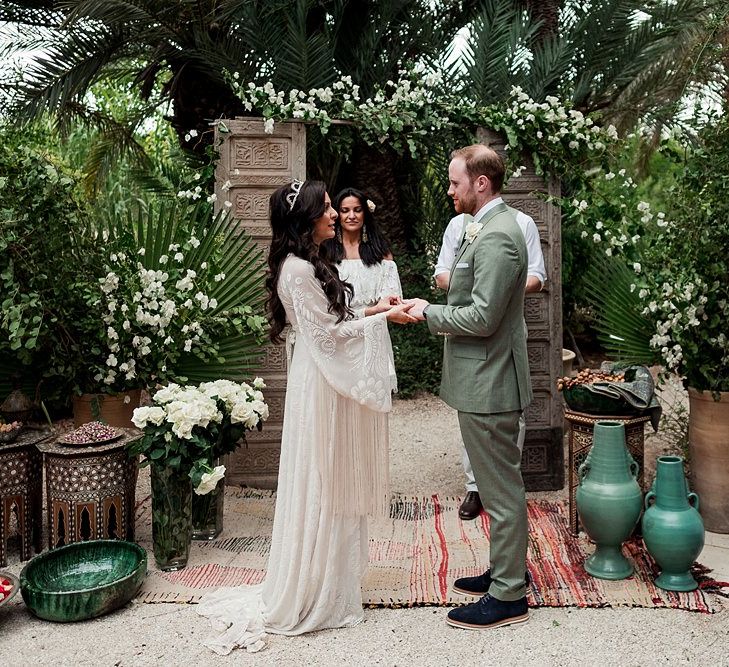 Outdoor Wedding Ceremony | Moroccan Rugs, Wooden Door Altar Wedding Decor | Bride in Rue de Seine Bridal Gown | Groom in Green Beggars Run Suit | Paradise Destination Wedding at Jnane Tamsna in Marrakech, Morocco | Nordica Photography | Matteo Castelluccia Film