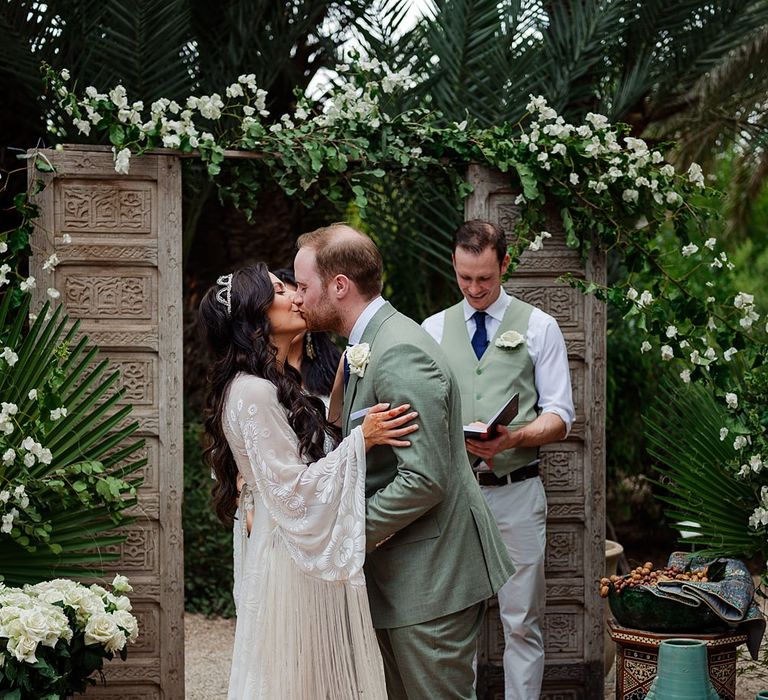 Outdoor Wedding Ceremony | Moroccan Rugs, Wooden Door Altar Wedding Decor | Bride in Rue de Seine Bridal Gown | Groom in Green Beggars Run Suit | Paradise Destination Wedding at Jnane Tamsna in Marrakech, Morocco | Nordica Photography | Matteo Castelluccia Film