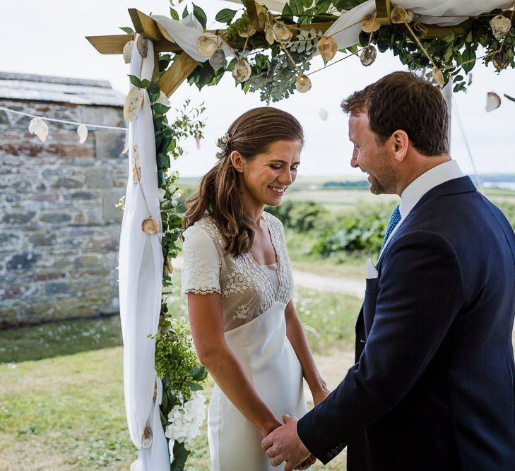 stretch tent wedding ceremony with DIY wooden altar covered in drapes, ivy and sea shells