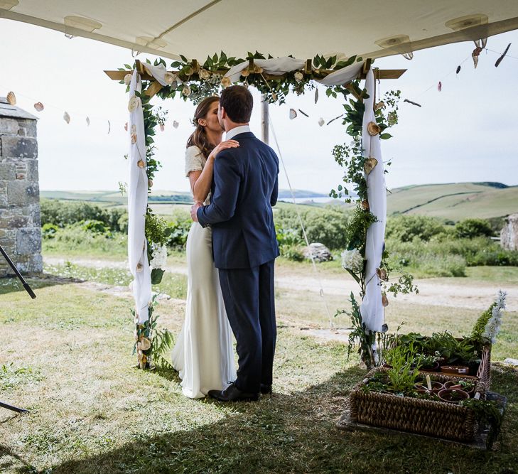 Bride and groom kissing at outdoor stretch tent wedding ceremony