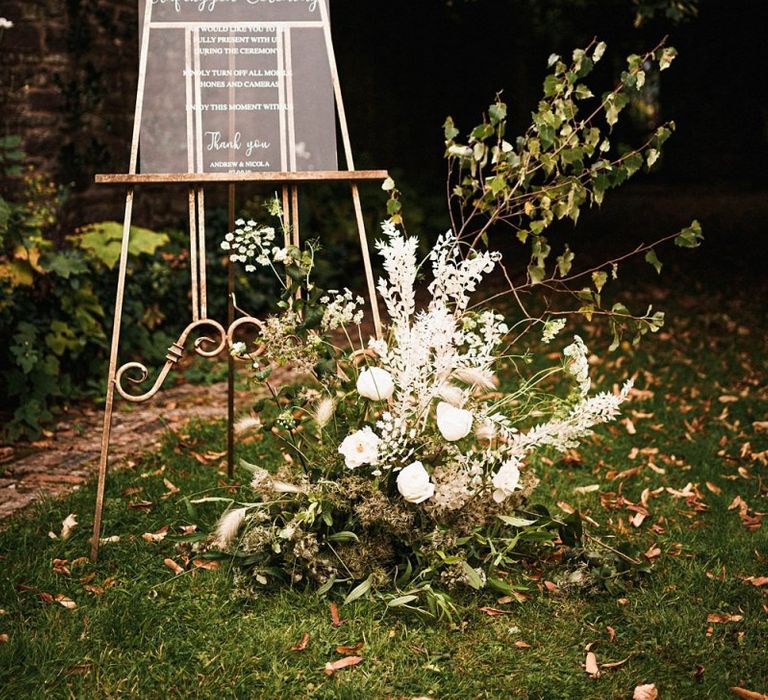 Acrylic unplugged sign with white floral decorations at outdoor Dewsall Court wedding