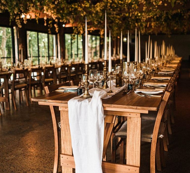 Barn reception venue details with large taper candles and relaxed fabric table runners