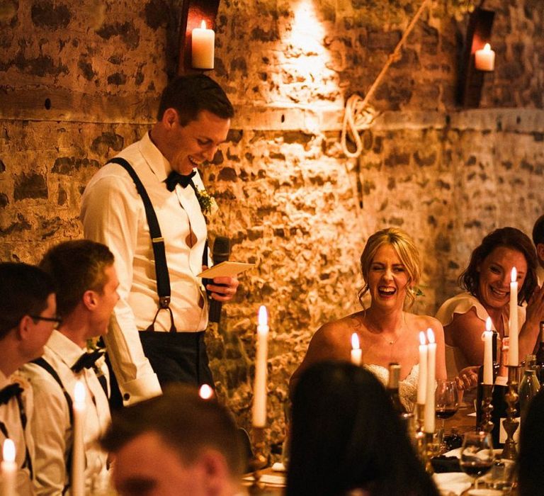 Grooms speech at relaxed barn reception with taper candle decoration