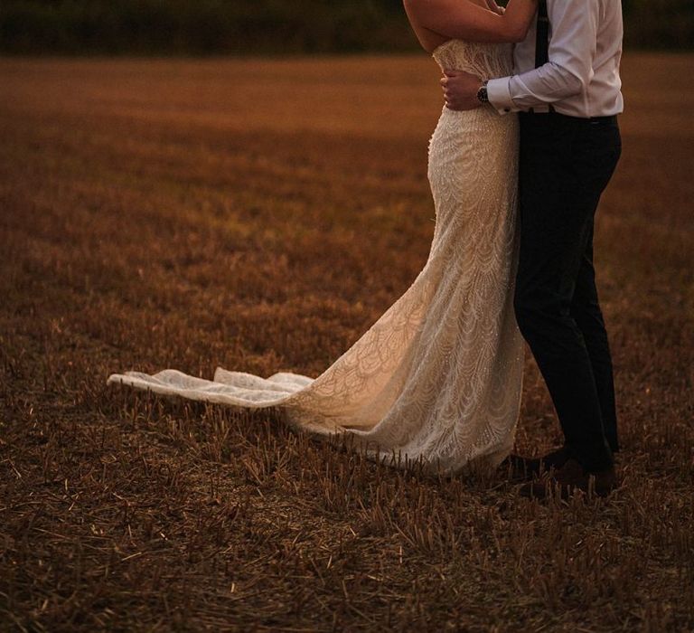 Bride and groom embrace for sunset shot at outdoor autumn day